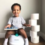 Toddler sitting and reading a book on the Kolcraft Tiny Steps Too 2-in-1 Activity Walker